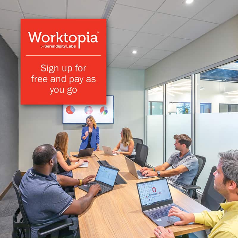 A woman presents to five colleagues with laptops in a modern office setting with glass walls and a red Worktopia sign. Discover flexible offices and meeting rooms at Serendipity Labs coworking—sign up for free, pay as you go.
